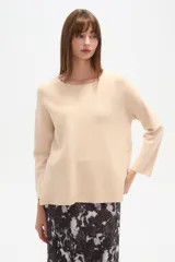 Sweater blanco liso, de corte holgado, con cuello a la base y broches decorativos en los laterales.