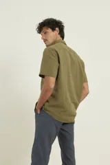 Camisa sport de manga corta color verde oliva, línea premium, con cuello clásico, cierre frontal con botones de coco y bolsillo de parche en el pecho. Confeccionada en lino y algodón.