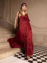 Vestido largo color borgoña con bordados florales a tono, escote en V y breteles finos. Diseño amplio con corte debajo del busto y falda escalonada. Incluye un pañuelo para la cabeza tejido al crochet en el mismo tono.