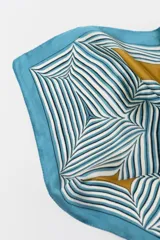 Pañuelo cuadrado de satén estampado con diseño geométrico en tonos celeste, blanco, negro y dorado.