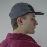 Gorra de cinco paneles con visera plana, color negro con secciones en verde y fucsia.