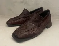 Mocasín de cuero color marrón con textura labrada y suela plana.