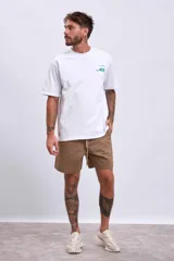 Remera blanca de manga corta con cuello redondo y un pequeño estampado gráfico en color verde en el pecho.