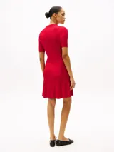 Minivestido rojo de tejido acanalado con cuello chomba, manga corta, corte evasé y botonadura dorada con logo grabado.