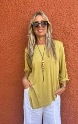 Buzo oversize color mostaza, con cuello redondo y mangas largas con puños anchos. Presenta un corte desigual en la base.