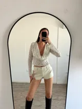 Top de fiesta color blanco, con escote drapeado y lentejuelas.