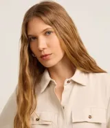 Vestido midi color beige confeccionado en sarga, con cuello camisero, manga corta, abotonado frontal, bolsillos utilitarios en el pecho y lazo en la cintura.