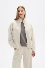 Campera negra de poliéster con cierre frontal, cuello alto, bolsillos con solapa en el pecho y cintura ajustable con cordón.