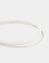 Set de dos vinchas rígidas para el pelo, una dorada lisa y otra con apliques de perlas.