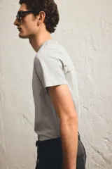 Remera gris de corte ajustado, cuello redondo y manga corta.