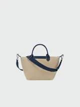 Cartera bandolera Longchamp modelo Le Pliage, tamaño S, confeccionada en gabardina de algodón color beige con detalles en azul marino. Presenta logo estampado en el frente, doble asa corta y correa larga ajustable y removible.