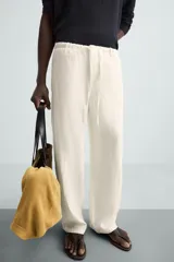 Pantalón de lino color crudo, de corte ancho, con cintura elástica ajustable con cordón, bolsillos laterales y trasero.