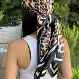 Pañuelo de seda con estampado animal print en tonos marrones y negros, con borde decorativo a rayas.