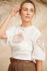 Camisa blanca de manga corta con aplicaciones de guipur en el frente y en las mangas.