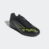 Championes de fútbol Adidas modelo F50 Club para pasto sintético, color negro con detalles en amarillo flúor y plateado. Presentan un exterior Fiberskin con estampado Sprintgrid y suela de caucho con tacos bajos.