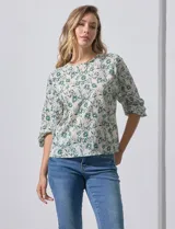 Blusa de gasa color blanco con estampado de hojas verdes, de mangas 3/4 abullonadas con puños elásticos.