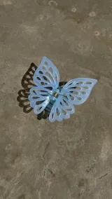 Broche para el pelo celeste con forma de mariposa y diseño calado en las alas.