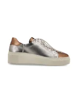 Sneaker de cuero graneado color plateado con detalles en color cobre en la puntera y el talón. Tiene suela elevada color hueso y cordones de algodón.