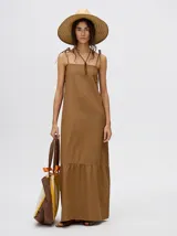 Vestido midi de denim algodón color marrón, con escote recto y tirantes finos ajustables con lazos. El corte es suelto y termina con un ruedo con semi-volado.