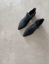 Botines negros de cuero vacuno con diseño tejido, punta fina y cierre lateral con hebilla. Taco de 5cm.