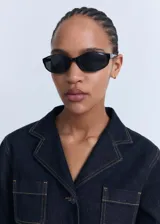 Chaqueta corta de denim azul oscuro, con cuello de solapa, dos bolsillos de parche en el pecho y cierre frontal de botones. Presenta costuras contrastantes y puños abotonados.