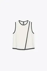 Blusa blanca sin mangas de crepe con cuello redondo y detalle de ribete negro en cuello, sisas y abertura frontal diagonal.
