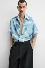 Camisa verde agua con estampado abstracto, corte relaxed fit, cuello solapa, manga corta y cierre frontal con botones.
