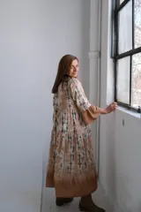 Vestido midi de corte holgado con estampado tie-dye en tonos beige, blanco y verde. Tiene cuello mao, mangas largas con puños acampanados y falda escalonada.
