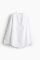 Camisa blanca de corte holgado con cuello en V y botones frontales.