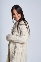 Saco tejido color crema con diseño de ochos y bolsillos frontales.