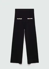 Pantalón negro de punto fino con diseño recto y largo, tiro medio, cintura elástica, ribetes en contraste y bolsillos de ribete delanteros con botones decorativos.
