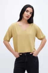 Remera color mostaza con escote en V, mangas abullonadas y corte cropped.