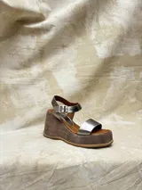 Sandalias de plataforma color plateado con base de gamuza marrón y hebilla ajustable en el tobillo.