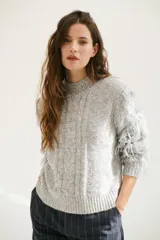 Sweater color arena de tejido de punto con cuello redondo y mangas largas con flecos.