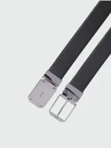 Cinturón negro con textura de piel, hebilla metálica plateada y diseño reversible.