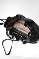 Bolso tipo sobre de cuero color rojo, con frunce superior y cierre con cordones. Tiene correa larga desmontable y bolsillo interno con cierre.