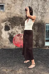 Body entallado color marrón oscuro con escote pronunciado en pico y manga sisa. Cierre en la parte inferior con botones a presión.