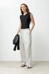 Pantalón de tiro alto, color plateado metalizado, con pliegues frontales y corte ancho y largo.