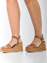 Sandalias de cuero color marrón con plataforma y taco de 8cm forrados en gamuza. Diseño con doble tira frontal y tira regulable al tobillo con hebilla metálica.