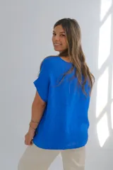 Blusa azul francia de lino, corte recto, con cuello redondo y mangas cortas con dobladillo.
