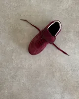 Sneakers bajas de cuero vacuno color bordó con suela marrón.