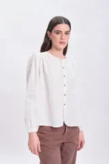 Blusa color crudo con textura, mangas largas abullonadas y cierre frontal con botones.