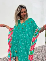 Túnica corta verde con estampado de flores rojas y detalles bordados. Mangas anchas con terminación en volados con estampado floral en tonos rosa y celeste.