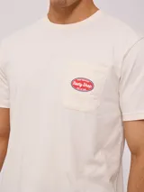 Remera color crema de manga corta con cuello redondo y bolsillo en el pecho con logo estampado de Rusty Shop Surf Services.