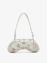 Bandolera de hombro con forma curva, color blanco, con estampado fotográfico de gatitos blancos de ojos azules. Posee correa ajustable y herrajes metálicos plateados.