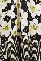 Vestido midi con estampado de flores blancas sobre fondo negro, mangas 3/4 y corte evasé.
