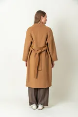 Tapado largo color camel, confeccionado en lana. Tiene doble botonadura, cuello con solapa y lazo para ajustar en la cintura.