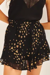 Minifalda negra con estampado de corazones dorados, cintura elastizada y volados en el ruedo.