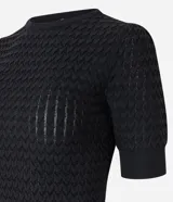 Blusa negra de manga corta con cuello redondo y textura de punto con patrón de corazones o escamas.