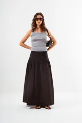 Falda larga de color negro, con cintura lisa y un amplio volado fruncido que comienza a la altura de la cadera, aportando volumen y movimiento.